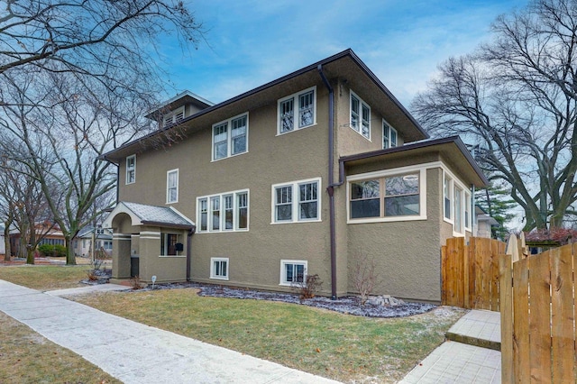 view of side of property featuring fence, a lawn, and stucco siding