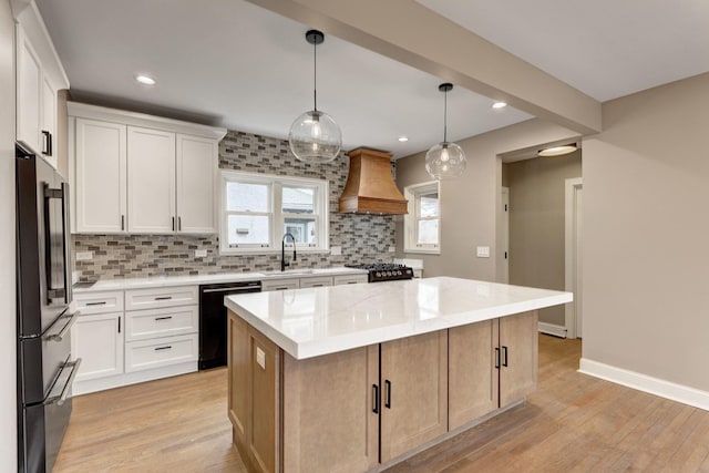 kitchen featuring a center island, tasteful backsplash, a sink, premium range hood, and black appliances