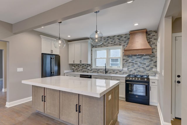 kitchen with gas range, light wood-style flooring, high quality fridge, premium range hood, and a sink