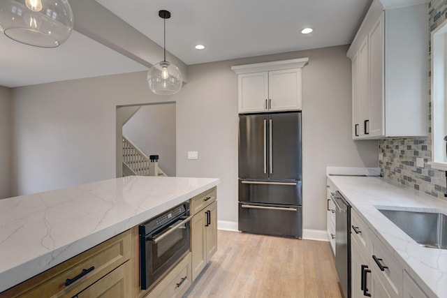 kitchen with decorative light fixtures, tasteful backsplash, light wood-style floors, freestanding refrigerator, and dishwasher