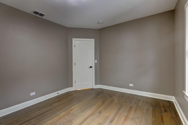 spare room featuring wood finished floors, visible vents, and baseboards