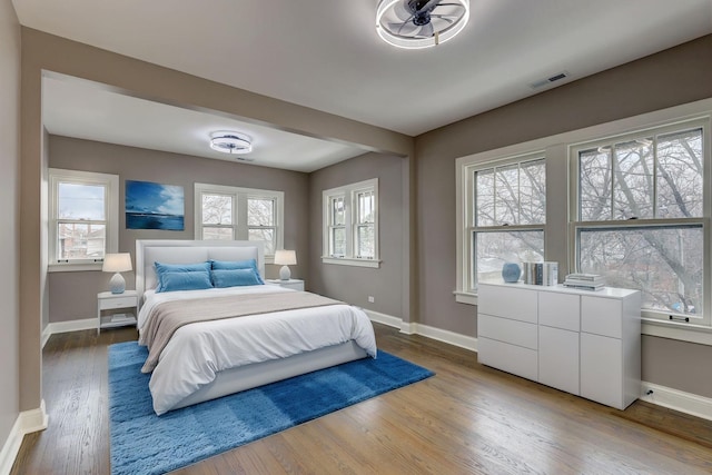 bedroom featuring wood finished floors, visible vents, and baseboards