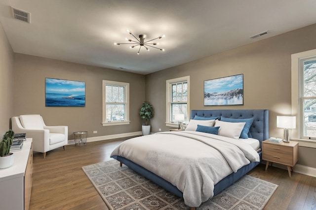 bedroom featuring a chandelier, wood finished floors, visible vents, and baseboards