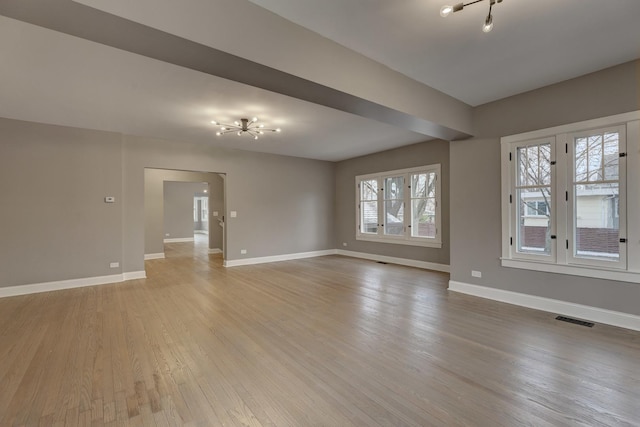 empty room featuring visible vents, light wood-style flooring, and baseboards