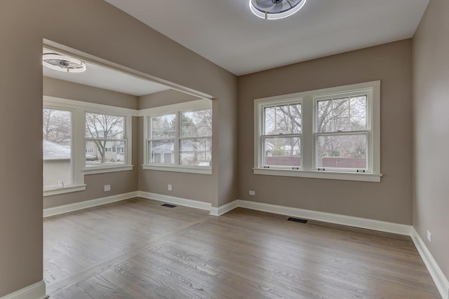 unfurnished room featuring visible vents, baseboards, and wood finished floors