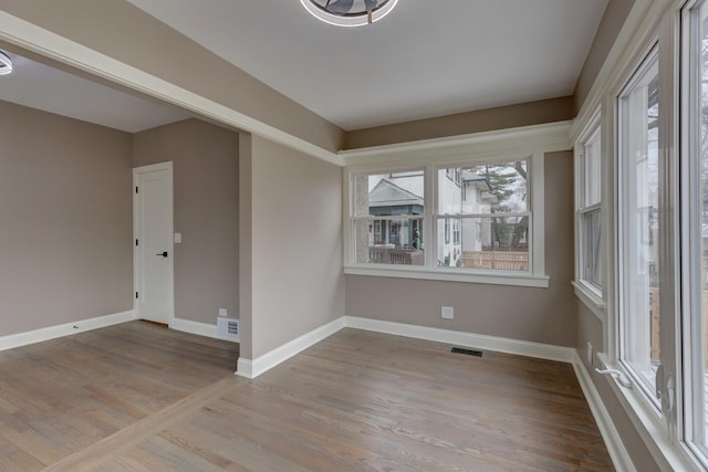 empty room featuring visible vents, baseboards, and wood finished floors