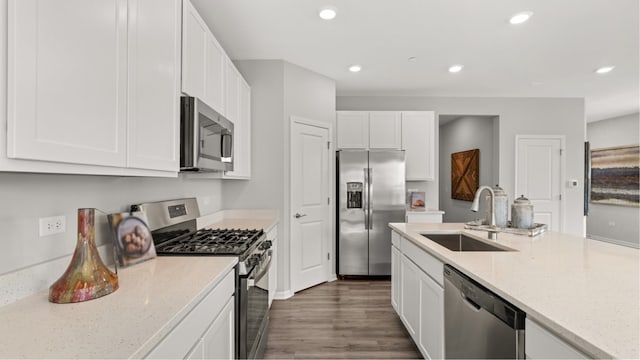 kitchen with sink, dark wood-type flooring, stainless steel appliances, light stone counters, and white cabinets