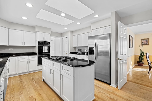 kitchen featuring appliances with stainless steel finishes, a skylight, a kitchen island, and white cabinets