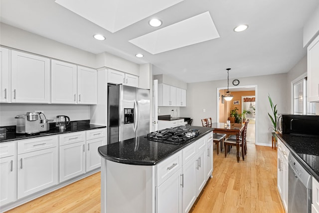 kitchen with a skylight, white cabinetry, hanging light fixtures, light hardwood / wood-style floors, and black appliances