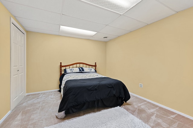 bedroom with light carpet and a drop ceiling