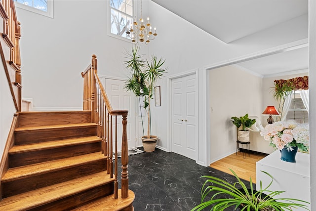 stairs with an inviting chandelier, ornamental molding, and plenty of natural light