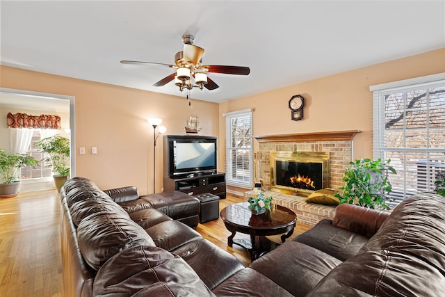 living room featuring a brick fireplace, light hardwood / wood-style floors, and a healthy amount of sunlight