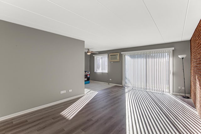 interior space with a wall mounted AC, ceiling fan, wood-type flooring, and brick wall