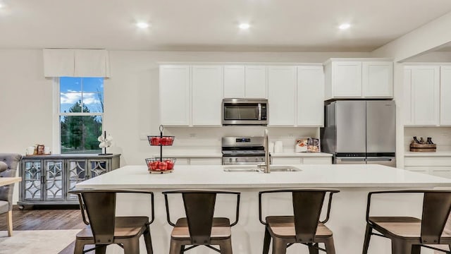 kitchen with a breakfast bar, white cabinetry, appliances with stainless steel finishes, and an island with sink