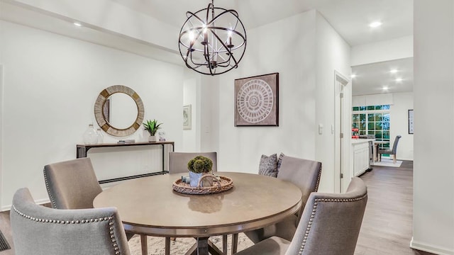 dining area with light hardwood / wood-style floors and an inviting chandelier