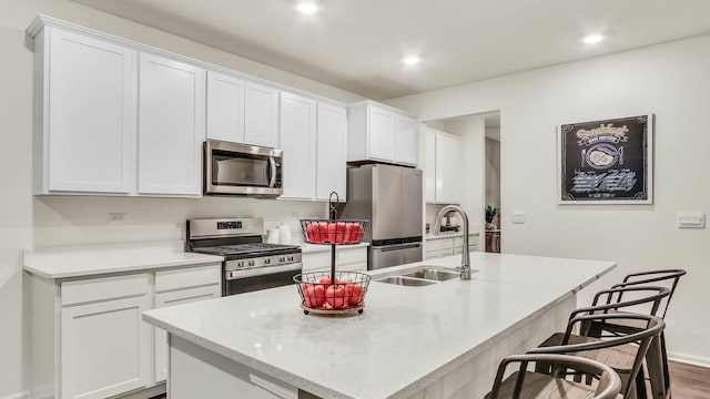 kitchen featuring white cabinets, appliances with stainless steel finishes, sink, and a center island with sink