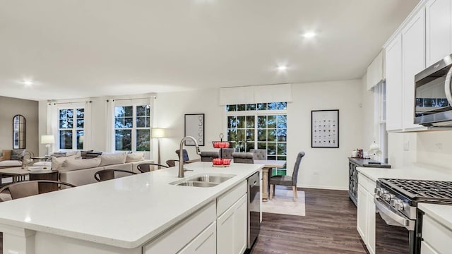 kitchen with white cabinetry, a center island with sink, appliances with stainless steel finishes, dark hardwood / wood-style floors, and sink