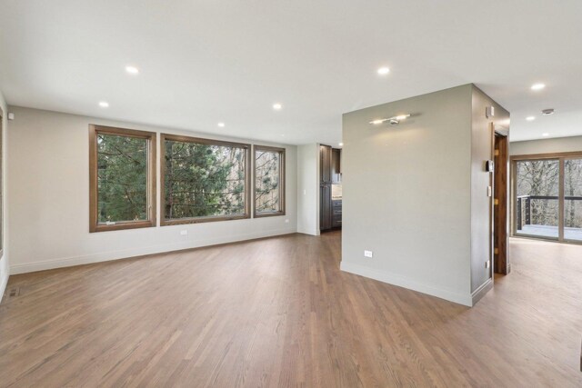 kitchen featuring baseboards, wall chimney exhaust hood, high end range, light countertops, and backsplash