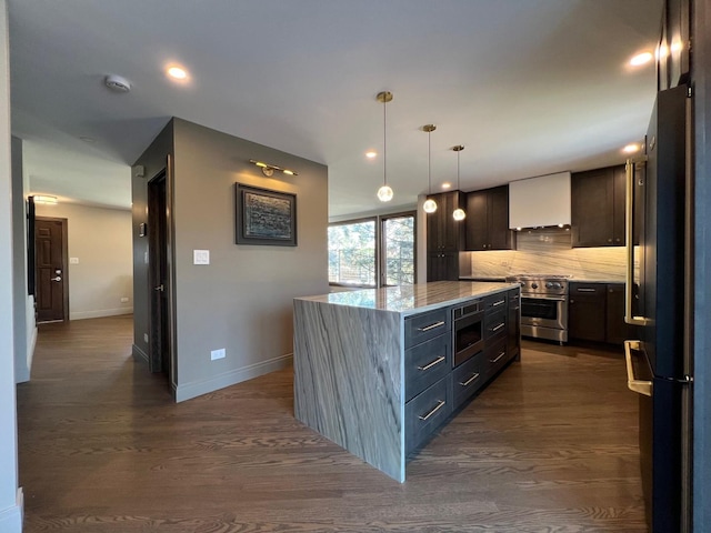 kitchen featuring dark wood-style floors, a kitchen island, stainless steel appliances, decorative backsplash, and wall chimney range hood