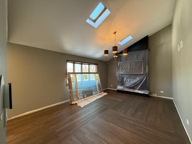 unfurnished room featuring high vaulted ceiling, a notable chandelier, baseboards, and wood finished floors