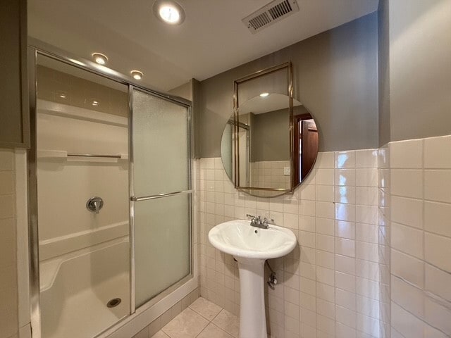 bathroom with a stall shower, visible vents, wainscoting, tile patterned floors, and tile walls