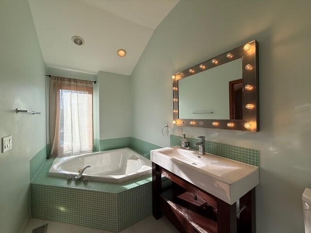 full bath with lofted ceiling, a garden tub, toilet, and vanity