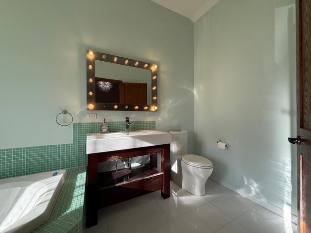 bathroom with tiled tub, vanity, toilet, and tile patterned floors