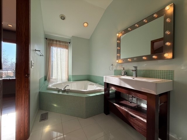 full bath with vaulted ceiling, tile patterned flooring, a garden tub, and vanity