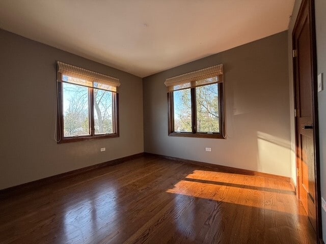 unfurnished room with baseboards and wood finished floors