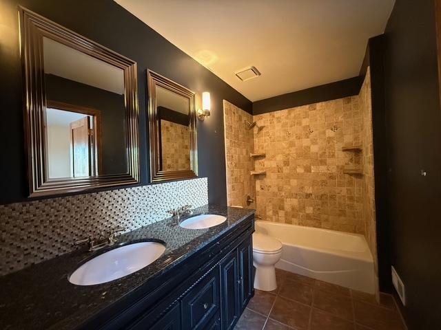 bathroom featuring tile patterned flooring, visible vents, tasteful backsplash, and a sink