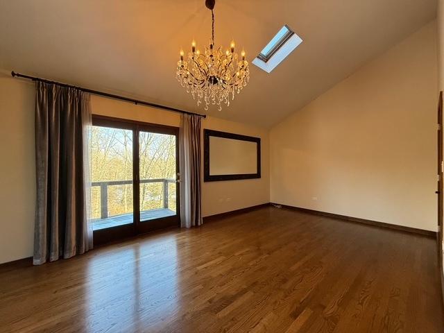 unfurnished room with dark wood finished floors, a notable chandelier, vaulted ceiling, and baseboards