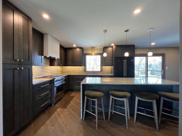 kitchen featuring black refrigerator, a sink, high end stainless steel range, dark wood-style floors, and a kitchen bar