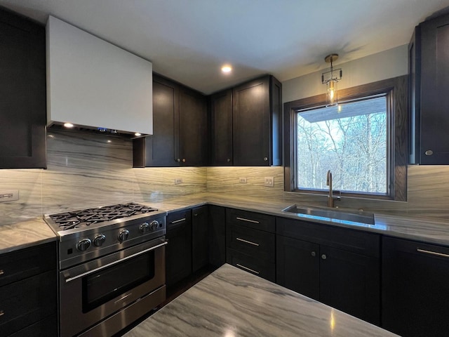 kitchen with light stone counters, decorative light fixtures, stainless steel range, tasteful backsplash, and a sink