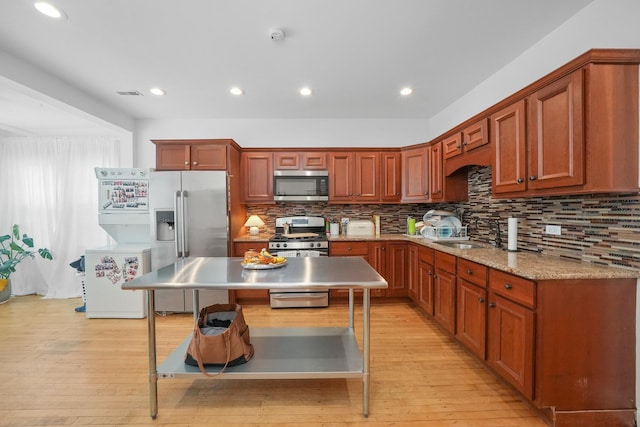 kitchen featuring a center island, backsplash, sink, appliances with stainless steel finishes, and light hardwood / wood-style floors