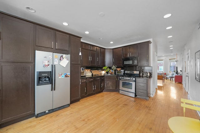 kitchen with backsplash, dark brown cabinetry, stainless steel appliances, and light hardwood / wood-style floors