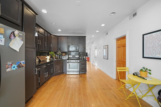 kitchen with appliances with stainless steel finishes, dark brown cabinetry, and light hardwood / wood-style floors