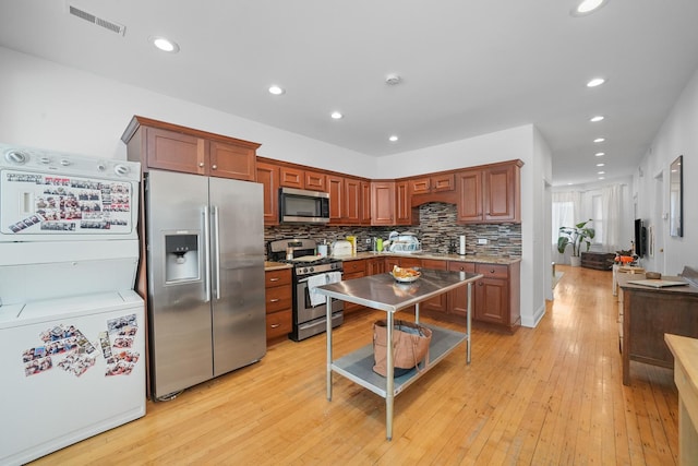 kitchen featuring washer / clothes dryer, decorative backsplash, stainless steel appliances, and light wood-type flooring