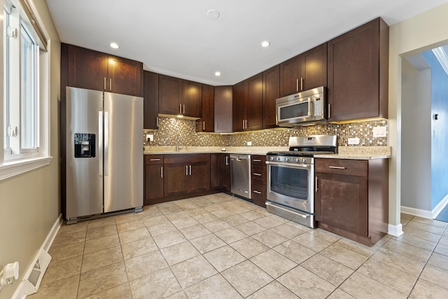 kitchen with light stone counters, dark brown cabinets, light tile patterned flooring, and stainless steel appliances