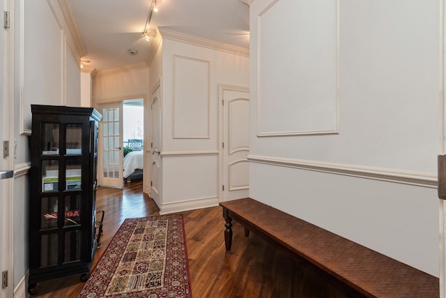 corridor featuring dark wood-type flooring, track lighting, and ornamental molding