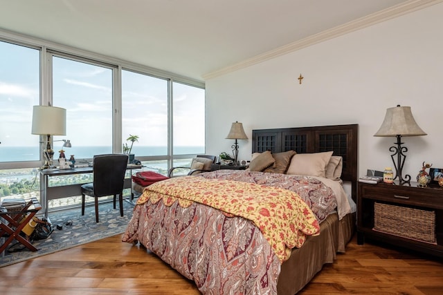 bedroom with floor to ceiling windows, a water view, ornamental molding, and wood-type flooring