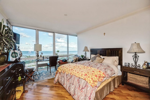 bedroom featuring expansive windows, a water view, ornamental molding, and wood-type flooring