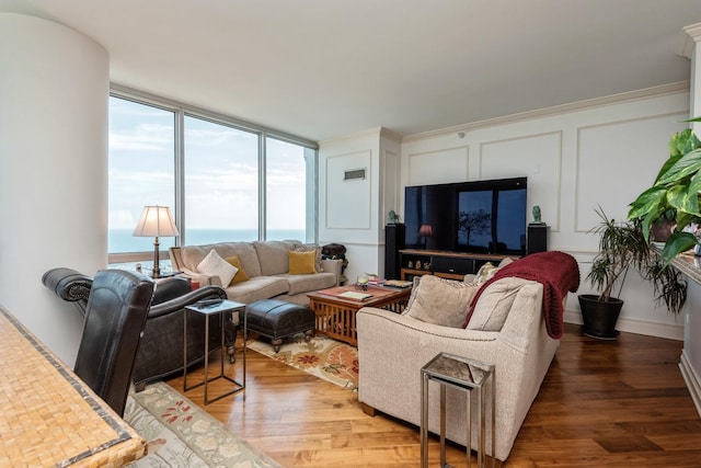 living room featuring wood-type flooring, a wall of windows, and crown molding