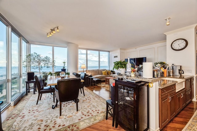 interior space featuring sink, wine cooler, light stone counters, expansive windows, and hardwood / wood-style floors