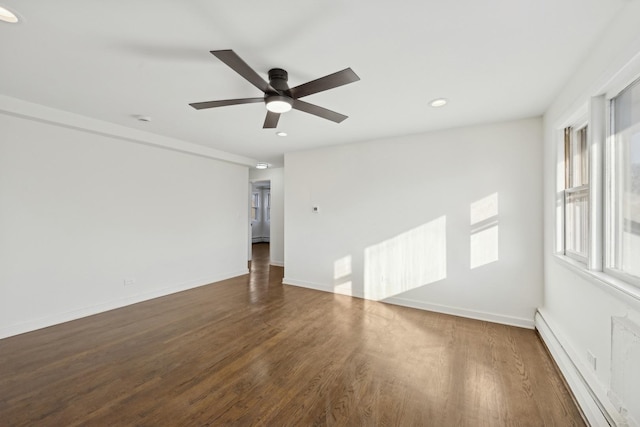 empty room featuring ceiling fan, dark wood-type flooring, and a baseboard heating unit