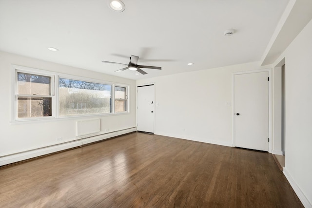 unfurnished room featuring ceiling fan, dark hardwood / wood-style flooring, and a baseboard heating unit