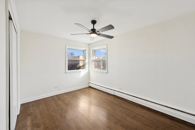 unfurnished bedroom featuring ceiling fan, dark hardwood / wood-style flooring, baseboard heating, and a closet