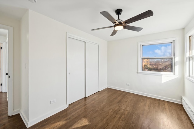 unfurnished bedroom with ceiling fan, a closet, dark hardwood / wood-style floors, and a baseboard heating unit