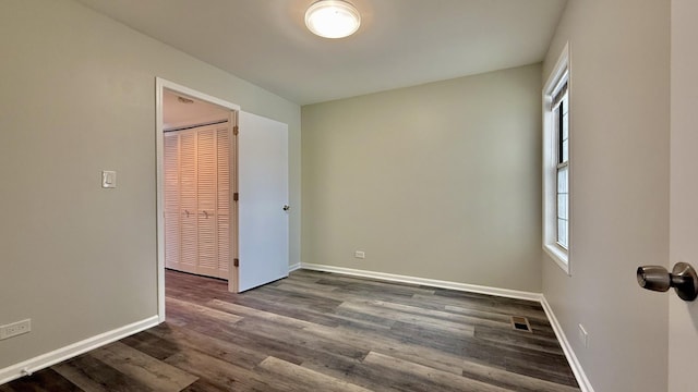 spare room with a wealth of natural light and dark wood-type flooring