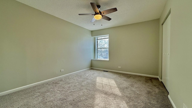 spare room with a textured ceiling, ceiling fan, and carpet