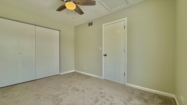 unfurnished bedroom featuring ceiling fan, light colored carpet, a closet, and a textured ceiling